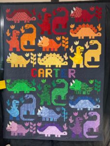 modern brightly colored quilt featuring dinosaurs