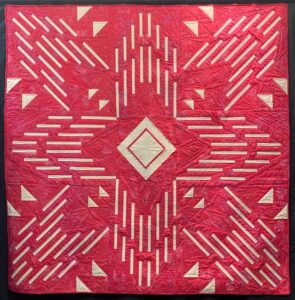 Modern hot pink quilt with white arrows bursting from center of quilt